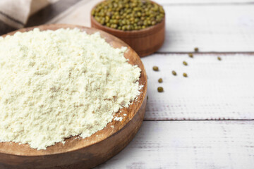Plate with mung bean flour and seeds on white wooden table, closeup. Space for text