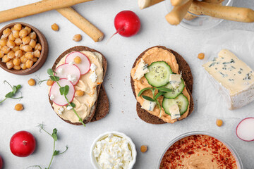 Delicious sandwiches with hummus and different ingredients on white background, flat lay