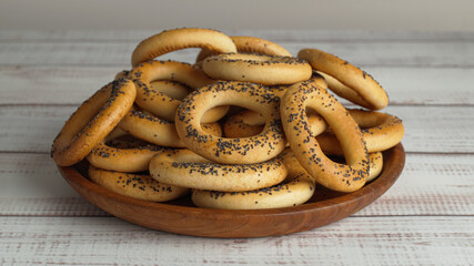 Plate with delicious ring shaped Sushki (dry bagels) on white wooden table, closeup