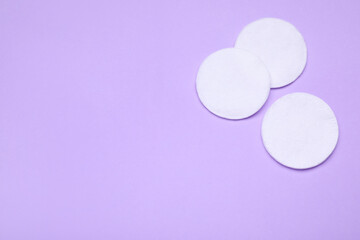 Cotton pads on lilac background, flat lay. Space for text
