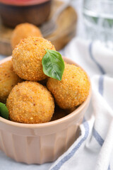 Bowl of delicious fried tofu balls with basil on white table, closeup
