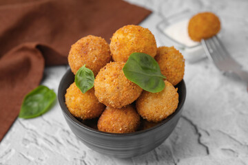 Bowl of delicious fried tofu balls with basil on textured table