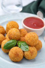 Delicious fried tofu balls with basil and sauce on plate, closeup
