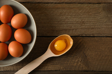 Raw chicken eggs on wooden table, flat lay. Space for text