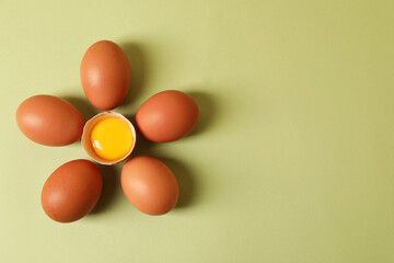 Flower made with cracked and whole chicken eggs on olive background, flat lay. Space for text