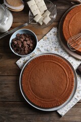 Delicious homemade sponge cake and different kinds of chocolate on wooden table, flat lay