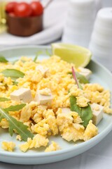 Delicious scrambled eggs with tofu and lime served on white table, closeup