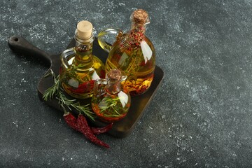 Cooking oil with different spices and herbs in jugs on light grey table, above view. Space for text