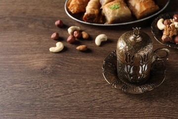 Fototapeta na wymiar Beautiful vintage cup holder, nuts and baklava dessert on wooden table, space for text