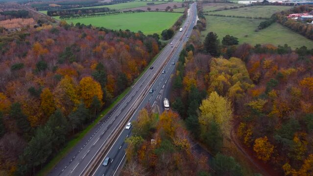 Dual carriageway road in Norfolk, A11 Thetford. Forest treetops with highway and cars, drone video. 
