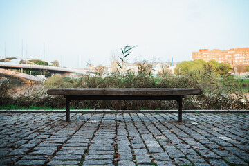 Obraz premium Front shot of a public bench next to the river in the city.