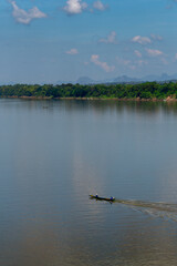 A fishing boat cruising on the Mekong River Nakhon Phanom, North East Thailand with the country of Laos on the right hands side. The Mekong River is a natural border between Thailand and Laos.