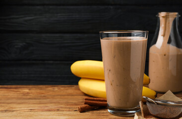 Tasty banana smoothie and ingredients on wooden table. Space for text