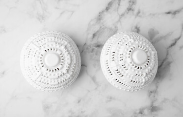 Dryer balls for washing machine on white marble table, flat lay