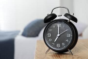 Naklejka premium Black alarm clock on wooden nightstand in bedroom, space for text