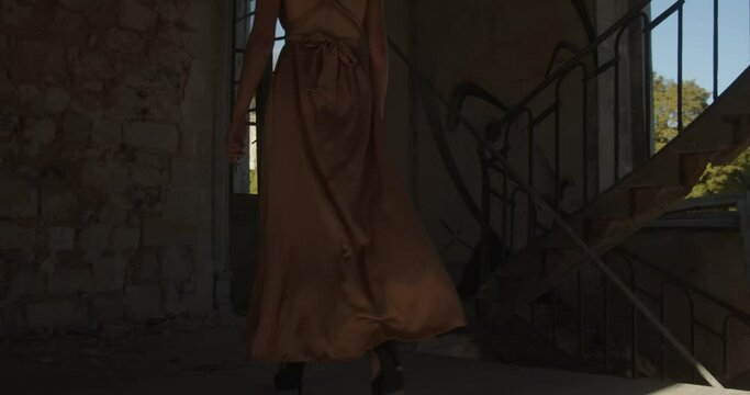 Woman Wearing A Backless Dress Is Walking Inside A Ruined Structure. Low Wide Angle