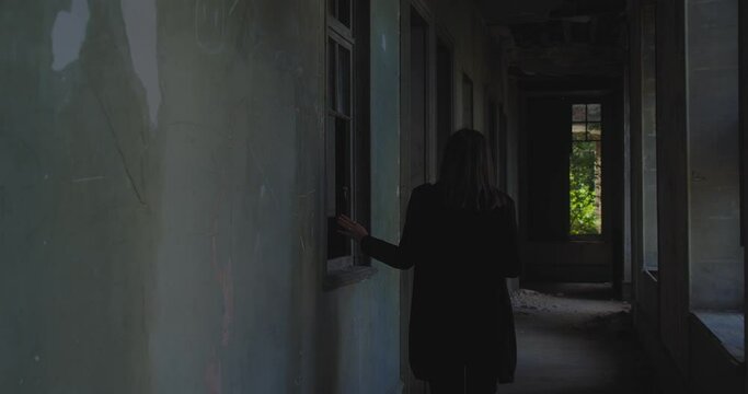 Woman exploring abandoned house. Haunted house concept. Gimbal, back view