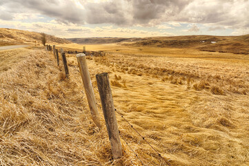 Dramatic Stormy landscape of farmland with a barbed wired fence