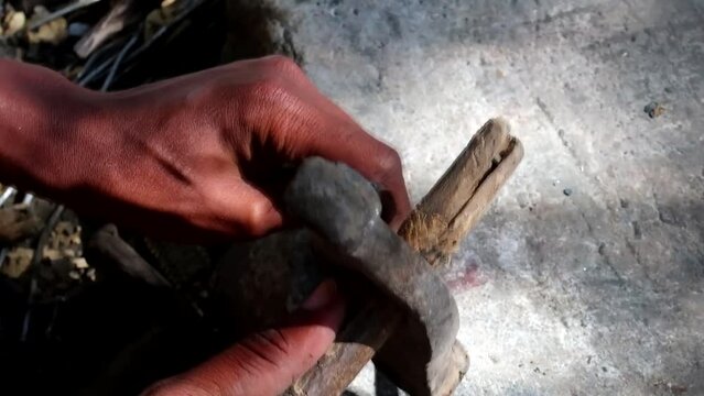 Close up of Tribal African person hitting a metal against a nail to make a sharp arrowhead