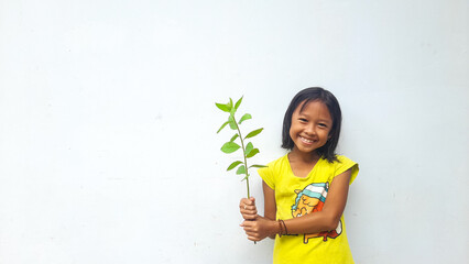 Little girl holding young plant.  Green Leaves. Ecology concept. Light color background.
