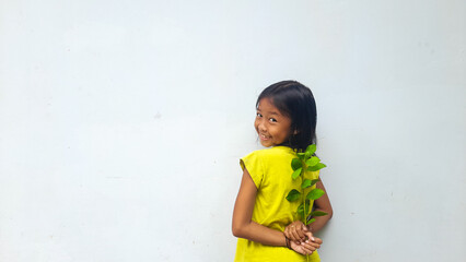 Little girl holding young plant.  Green Leaves. Ecology concept. Light color background.