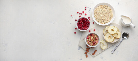 Obraz na płótnie Canvas Tasty granola with oat flakes, cranberries, apple chips and milk on light background with space for text