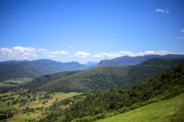 Fototapeta na wymiar blue sky and clouds above green valley vista