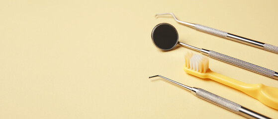 Brush and dental tools on beige background with space for text, closeup