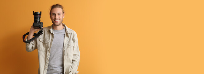 Young male photographer on orange background with space for text