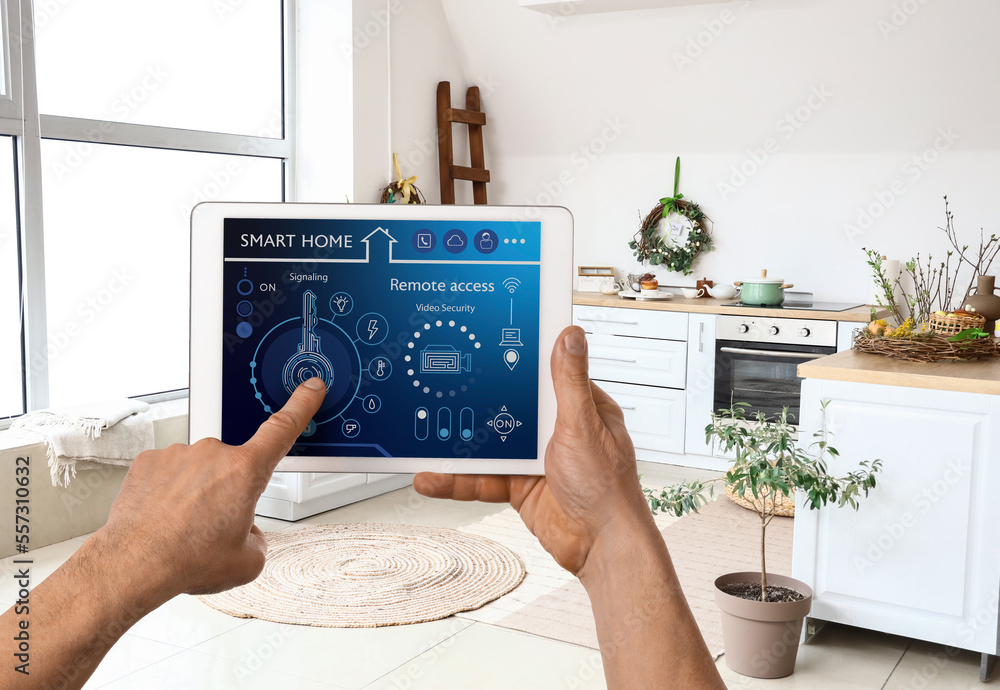 Poster man's hands holding tablet computer with smart home security system on screen in room