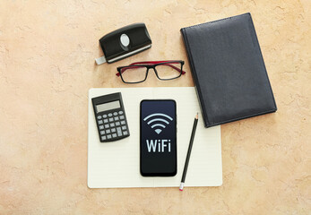 Stationery supplies, eyeglasses and mobile phone with WiFi symbol on color background