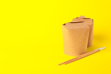 Boxes with Asian food and chopsticks on color background