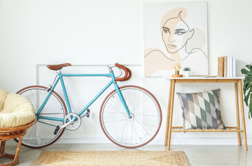 Interior of light living room with bicycle, table and picture