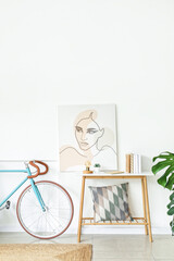 Interior of light living room with bicycle, table and picture