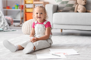 Fototapeta premium Cute little girl with felt-tip pens sitting on floor at home