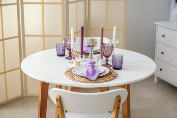 Beautiful setting, candles and gypsophila flowers on white table in light room