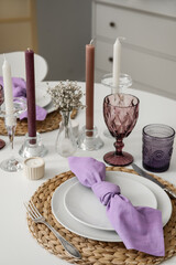Plate with napkin, cutlery and glasses on white table, closeup