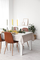 Fototapeta na wymiar Table with festive setting and floral decor in light room interior