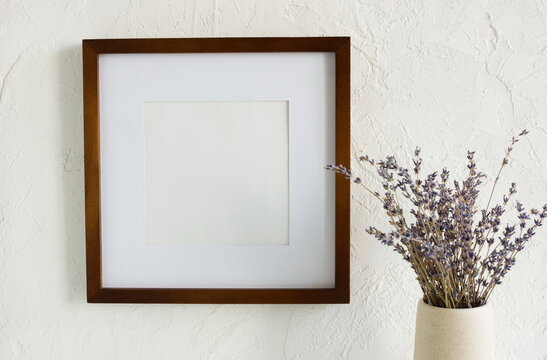 Portrait frame mockup with copy space for artwork, photo, painting, print presentation and lavender flowers in a vase near white textured wall .