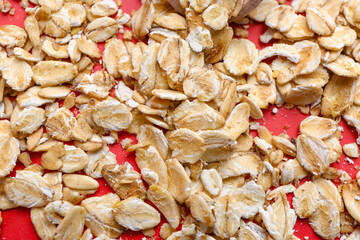 Scattered raw oatmeal on red background, closeup