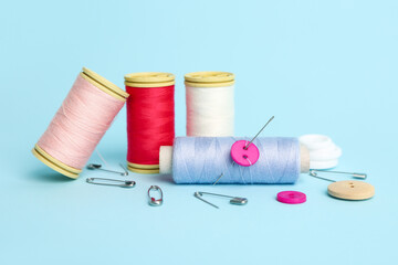 Set of sewing supplies with thread spools on color background
