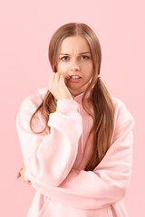 Young woman in hoodie biting nails on pink background, closeup