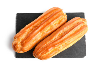 Slate board with tasty eclairs on white background