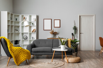 Interior of modern living room with black sofa, armchair and shelving unit