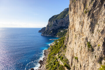 Fototapeta na wymiar Rocky Coast by Sea at Touristic Town on Capri Island in Bay of Naples, Italy. Sunny Day.