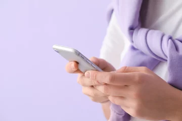 Poster Young woman using mobile phone on lilac background, closeup © Pixel-Shot