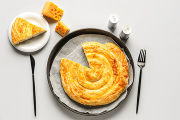 Plates with delicious cheese pie and cutlery on white background