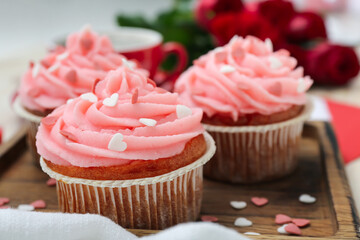 Tasty cupcakes for Valentine's Day on wooden board, closeup