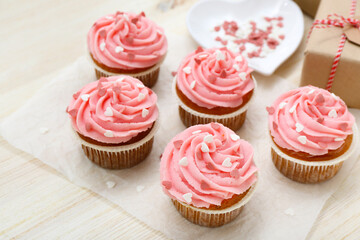 Baking paper with cupcakes for Valentine's Day on wooden background, closeup