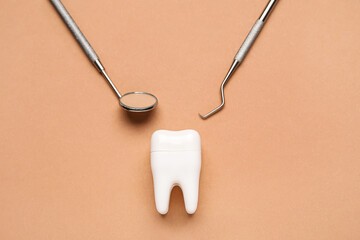 Plastic tooth with dental tools on brown background - obrazy, fototapety, plakaty